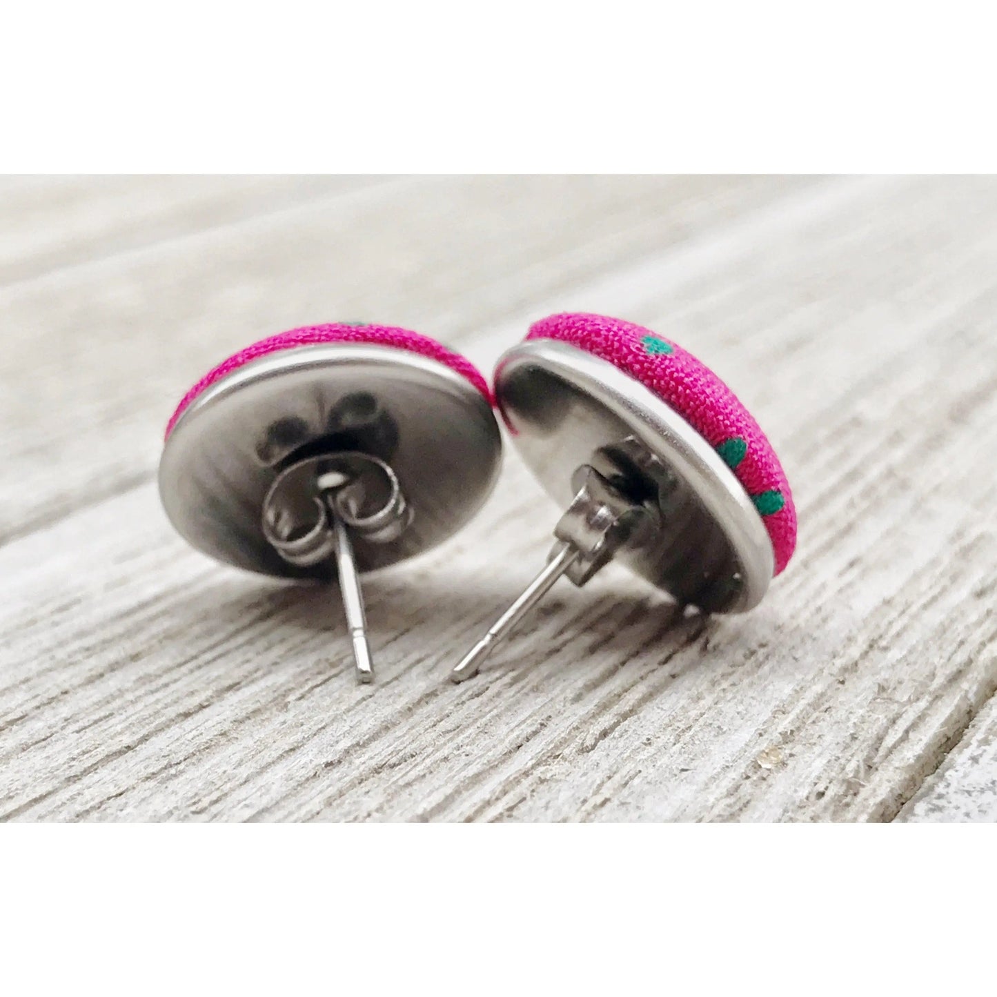 Pink earrings with metal posts on a wooden surface