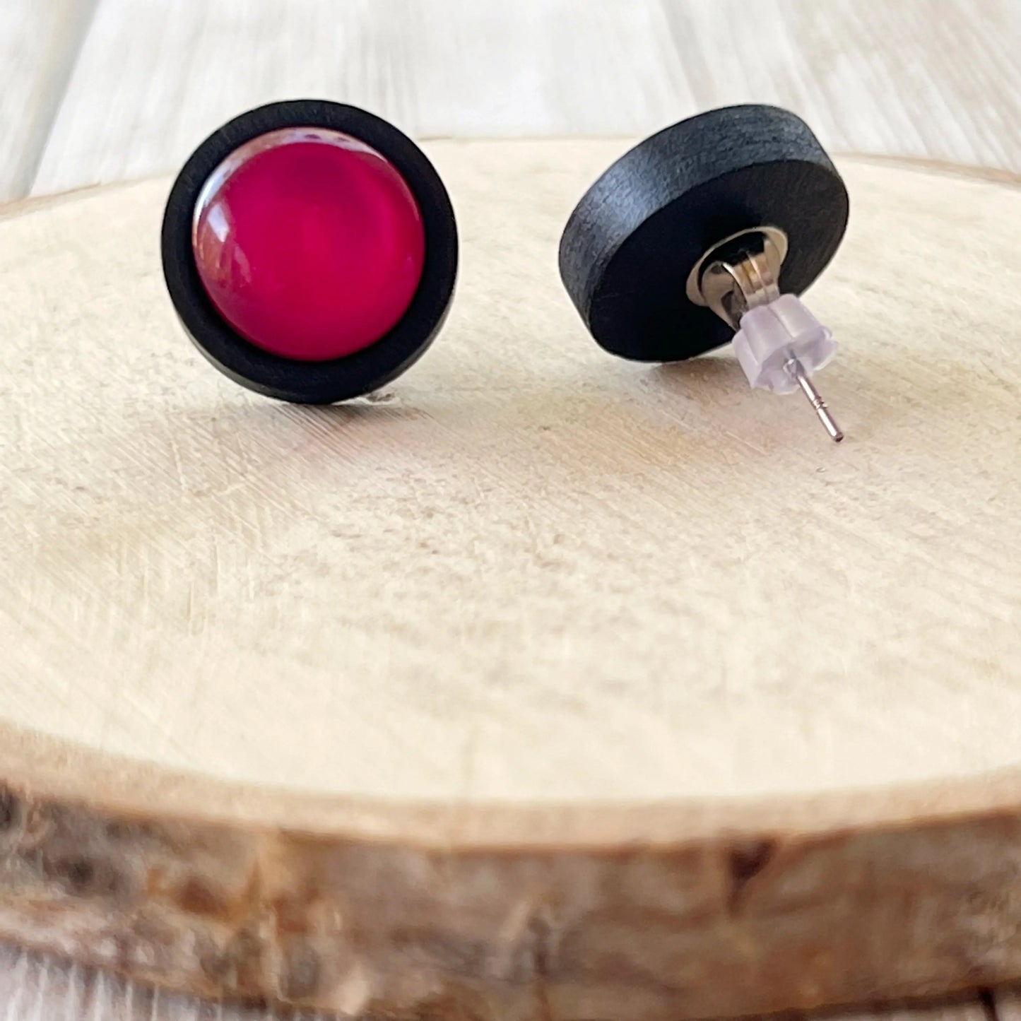 Black earrings with pink centers on a wooden surface showing back of earrings