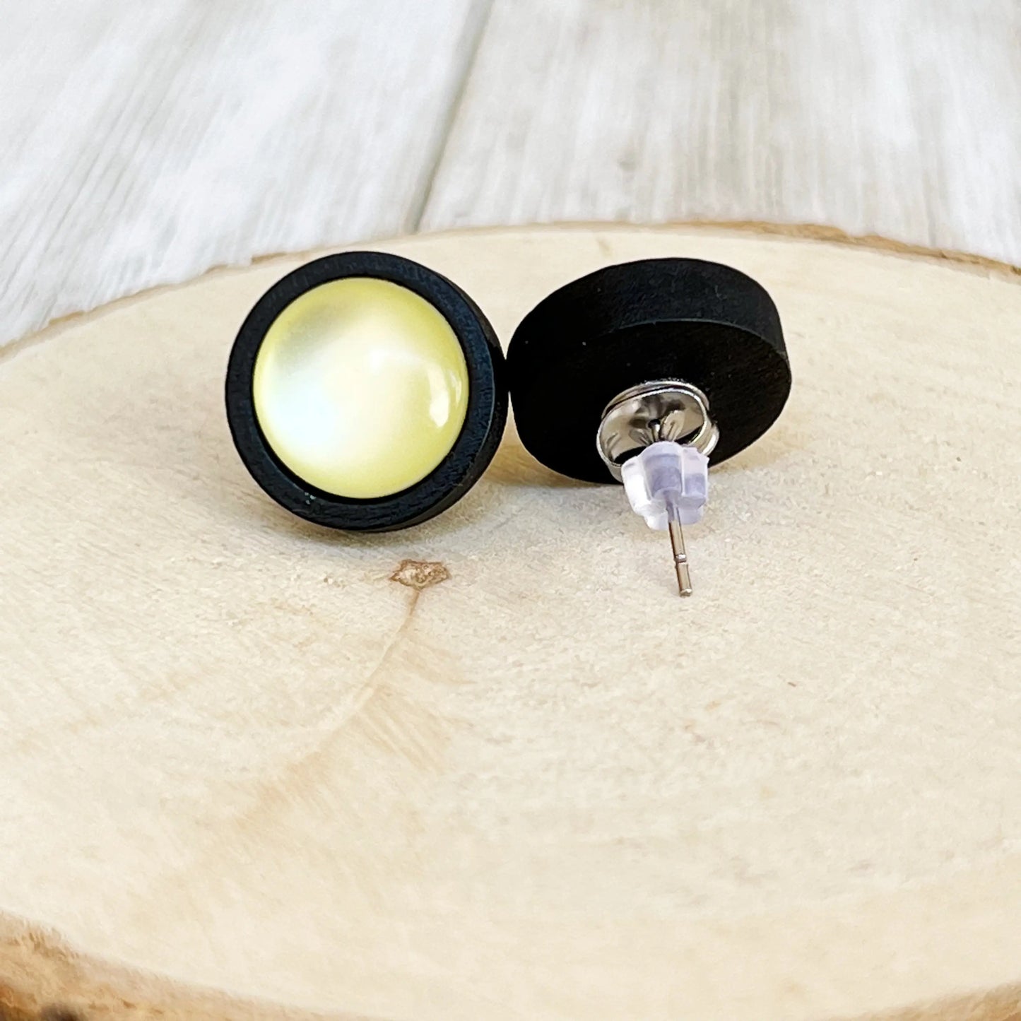 Back of black and yellow earrings on a wooden surface