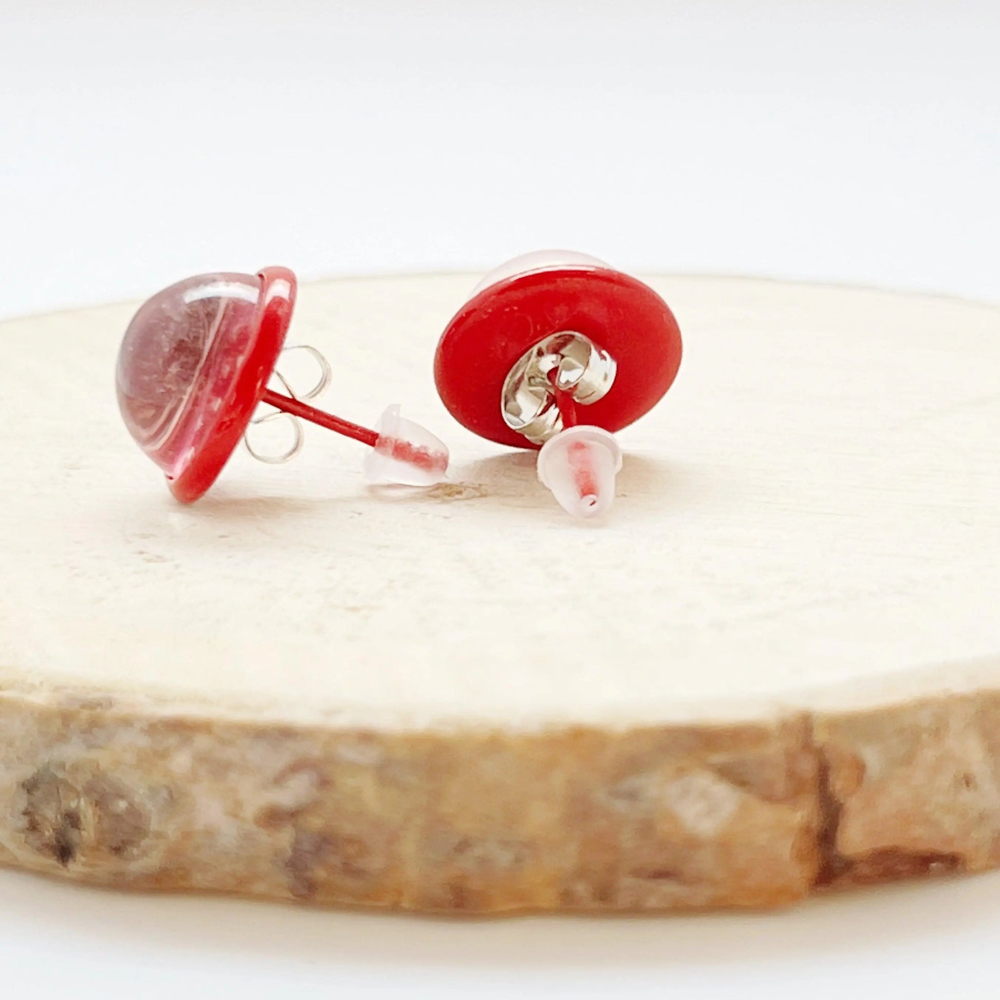 Back of red heart earrings on a wooden surface with a white background