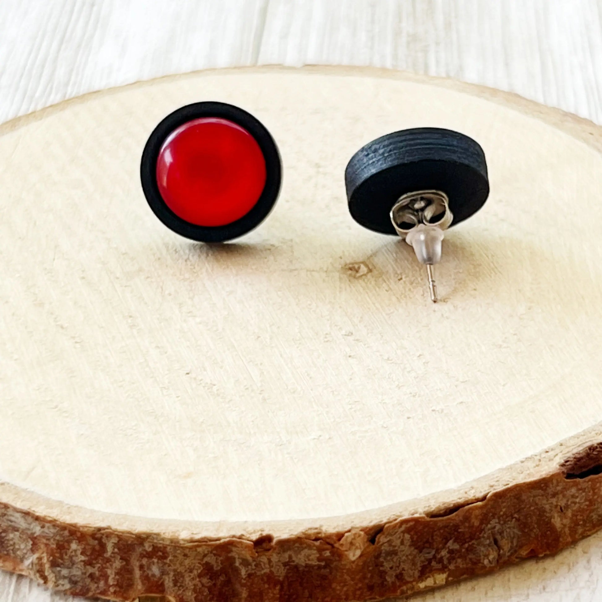 Black and red circular earrings on a wooden surface showing back of the earrings 