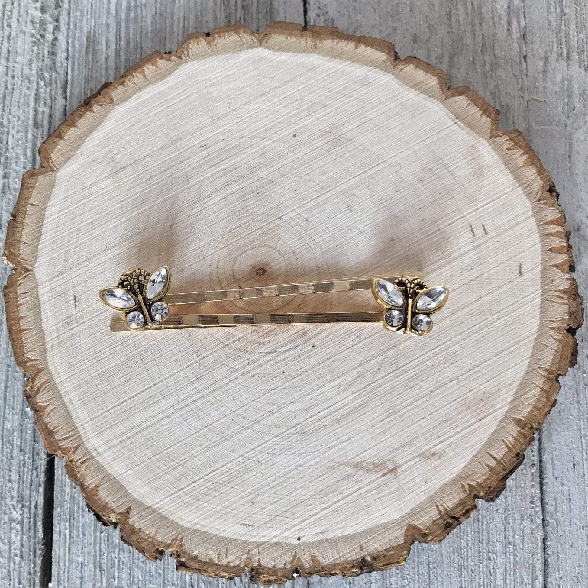 Set of two butterfly hair clips on wood background with green leaves