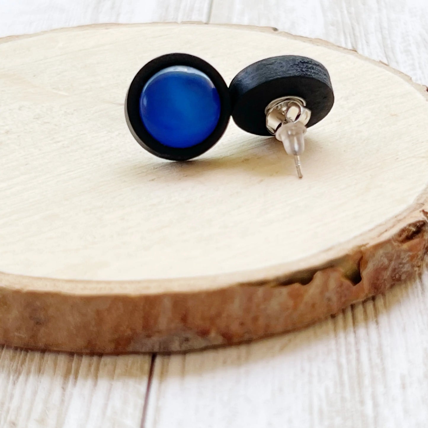 Back of black earrings with blue stones on a wooden surface