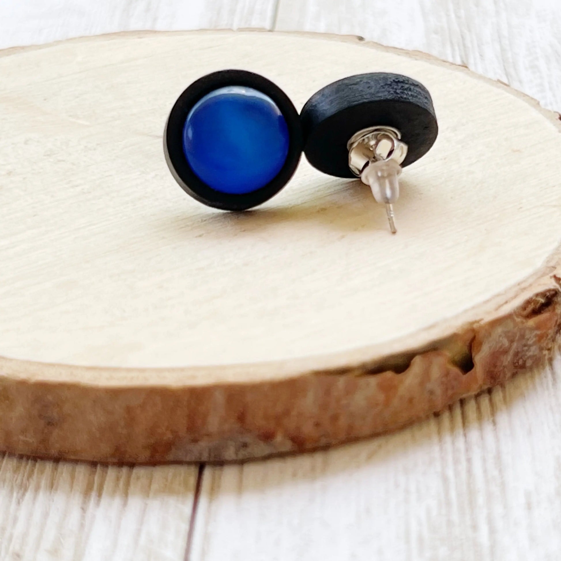 Back of black earrings with blue stones on a wooden surface