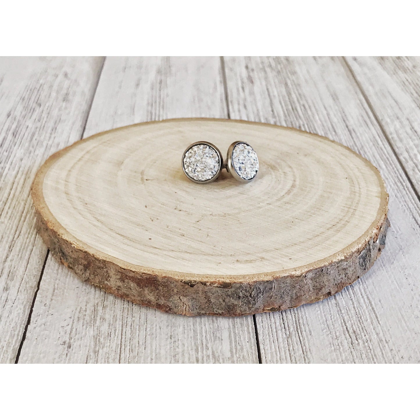 Pair of silver earrings with silver stones on a wooden surface