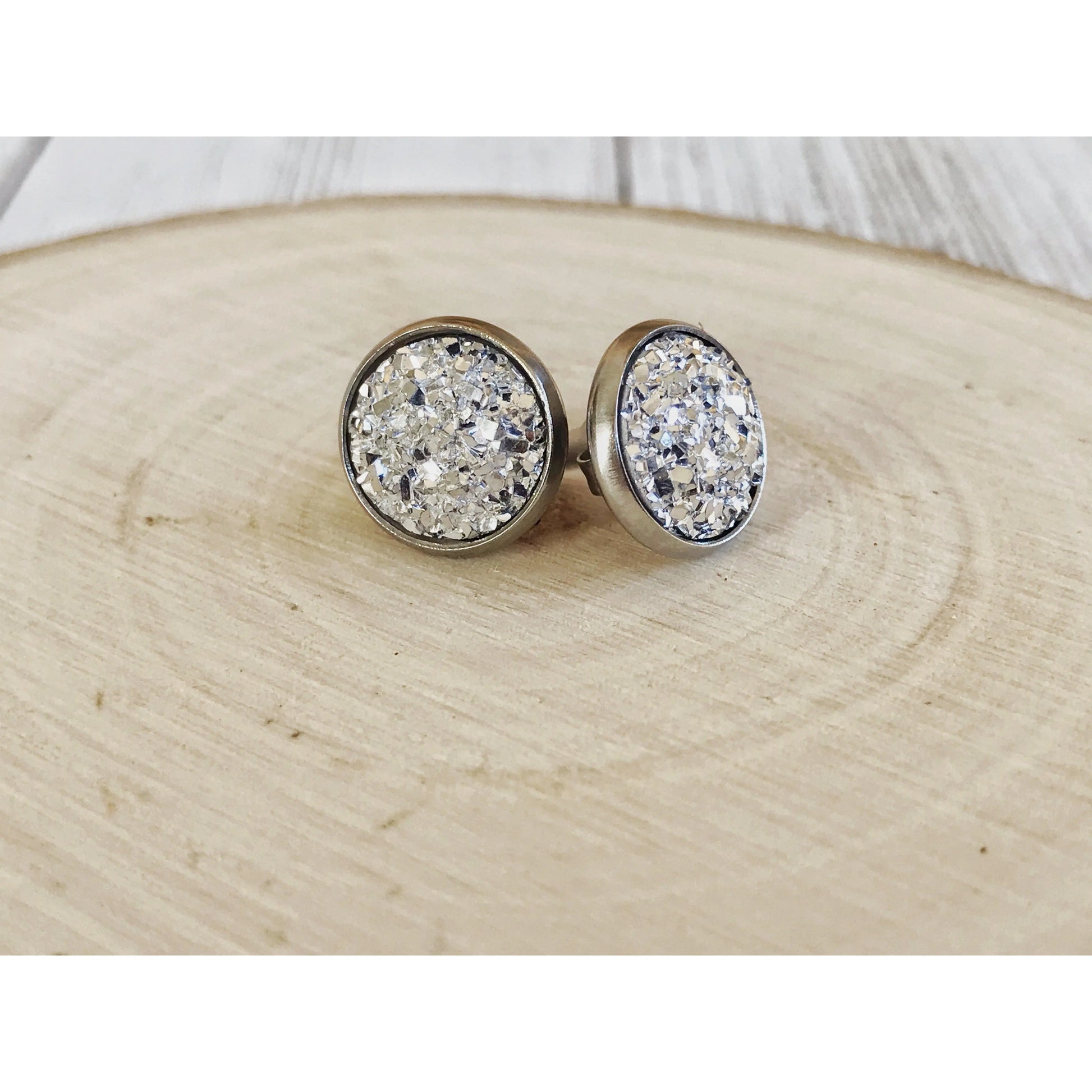 Pair of round earrings with crystal-like stones on a wooden surface