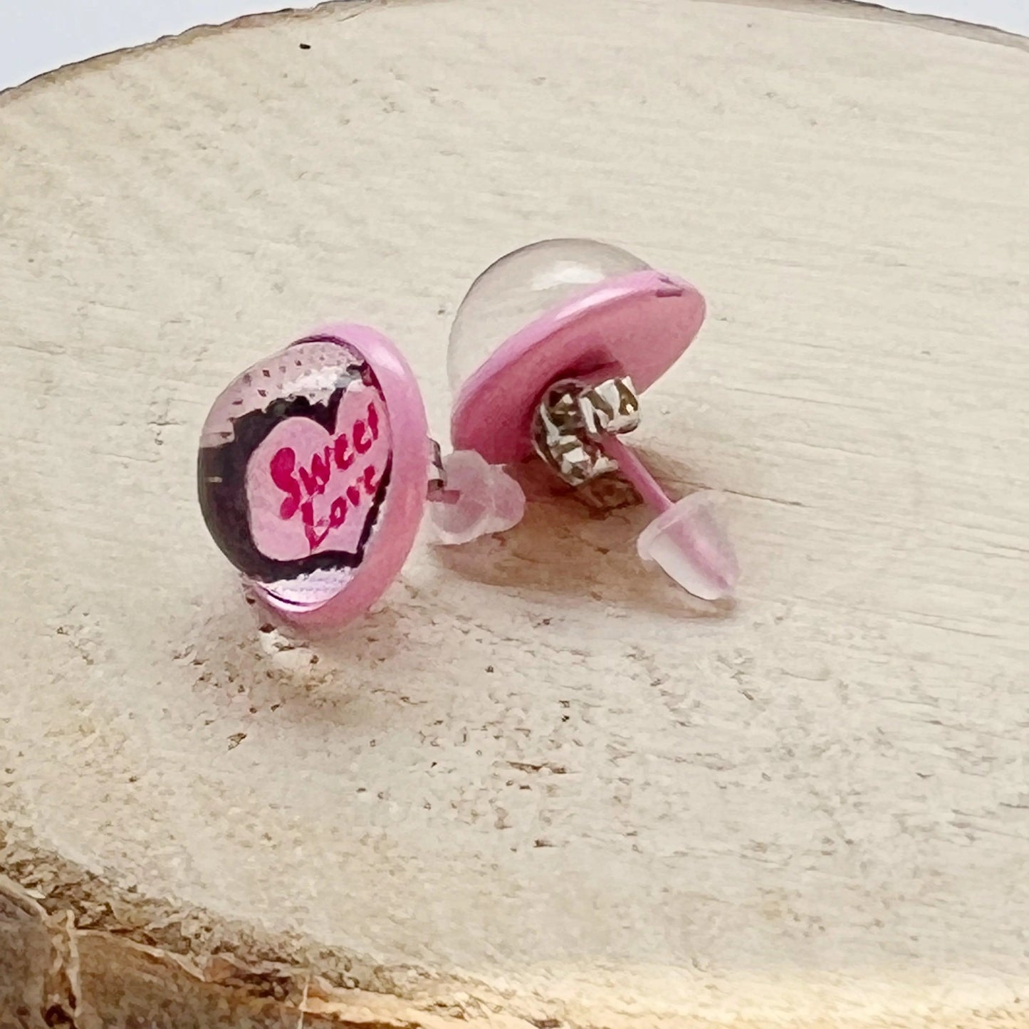 Back of pink earrings with heart design on a wooden surface