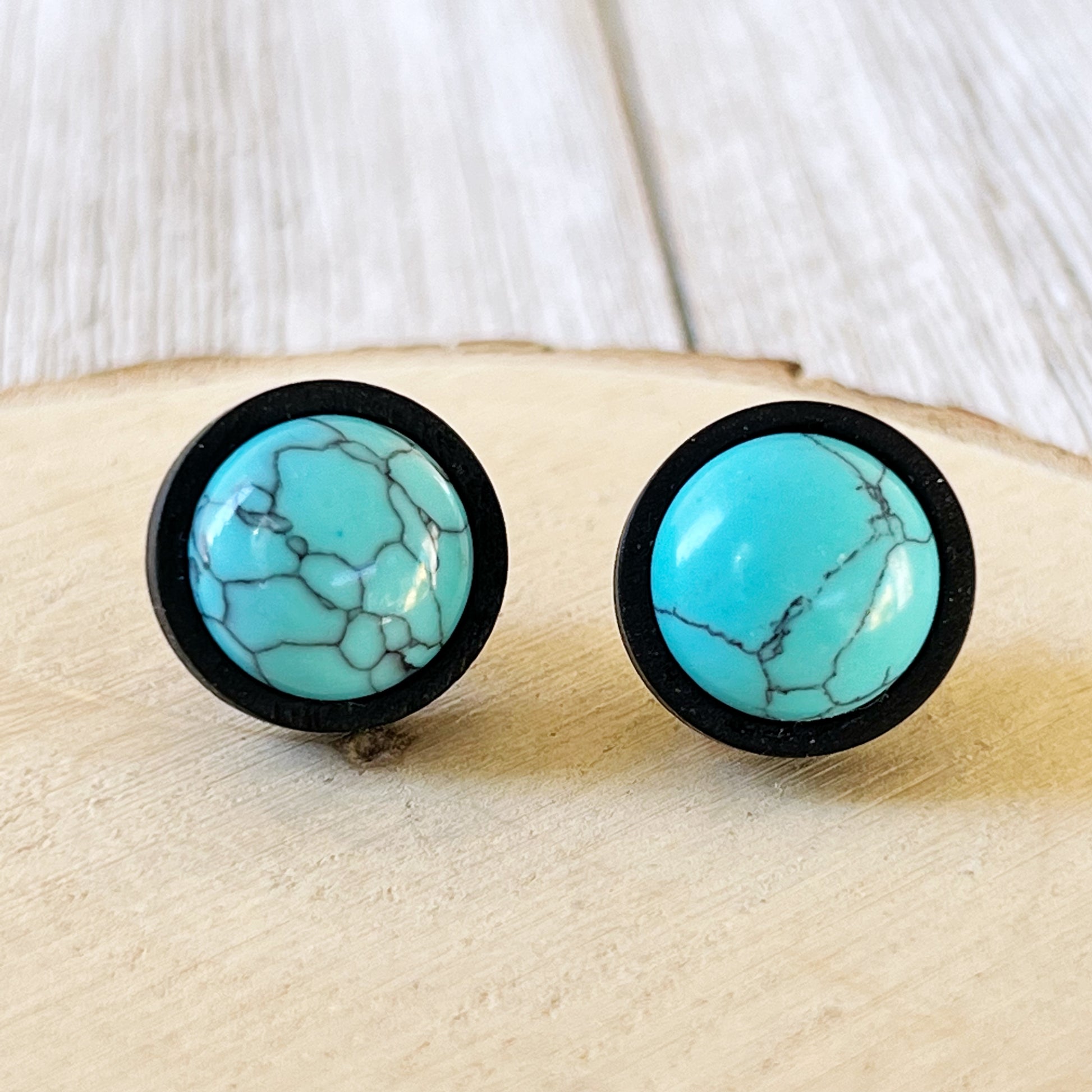 Black wood stud earrings with faux turquoise centers displayed on a wood background