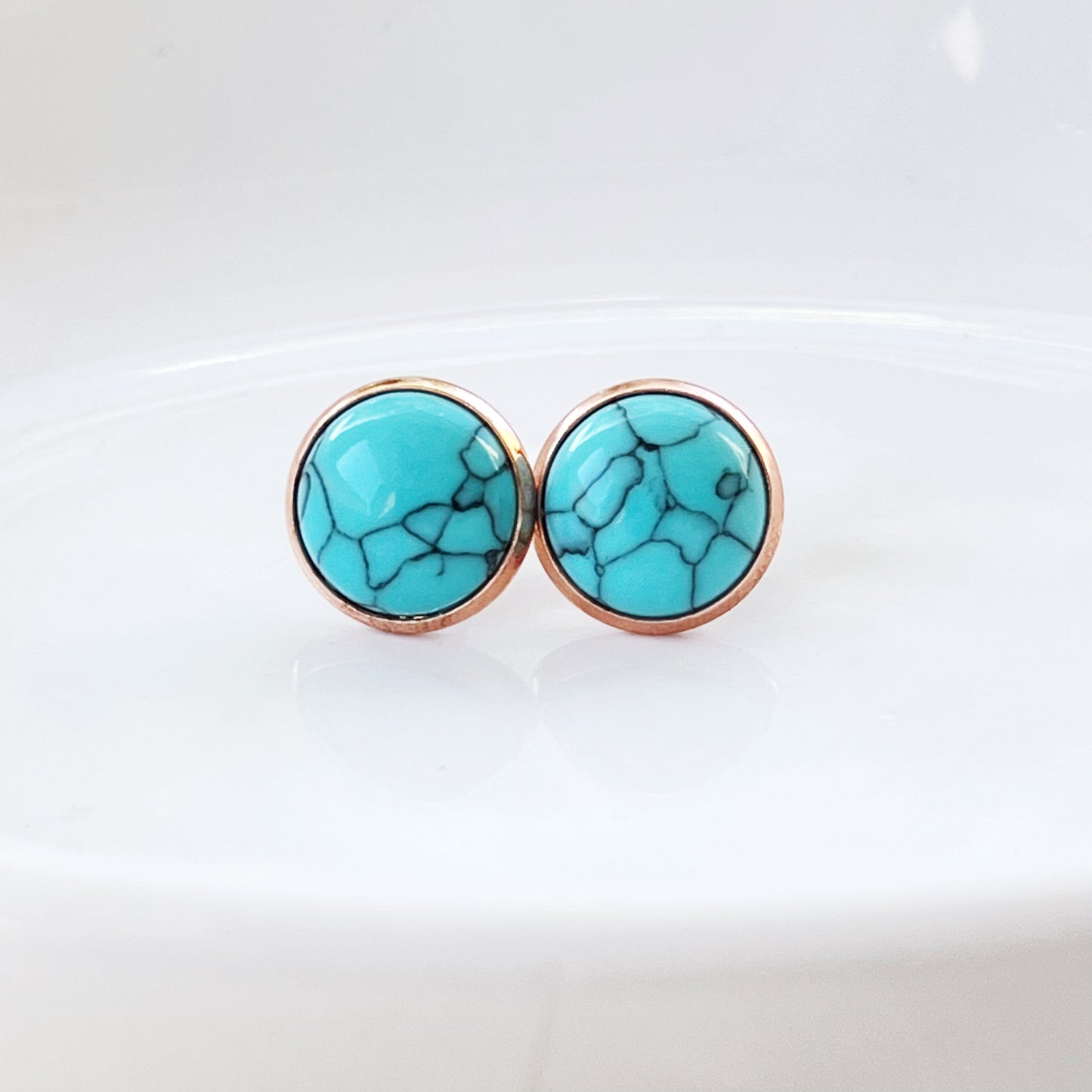 Round turquoise rose gold stud earrings displayed on a white surface