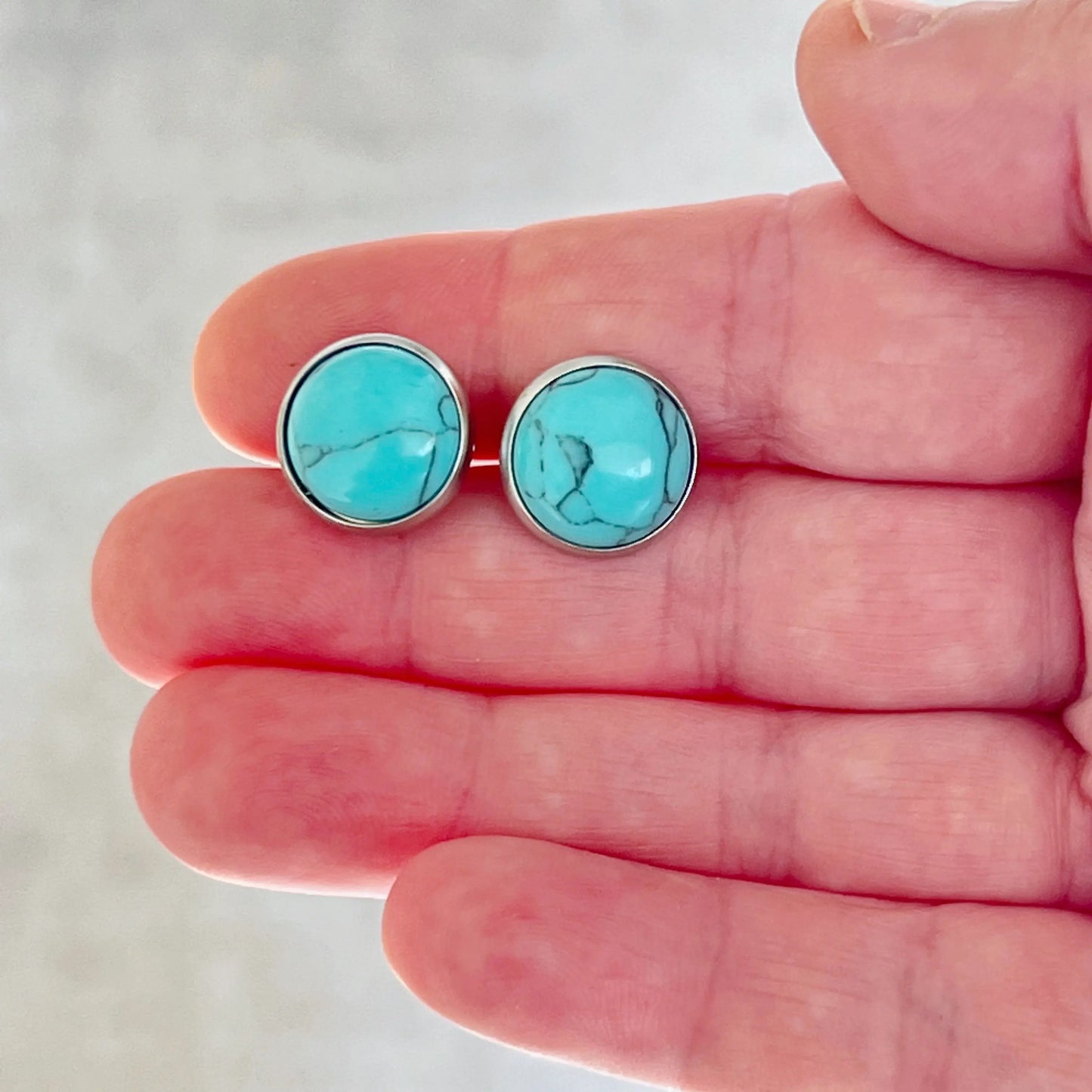 Turquoise 12mm Silver Stud Earrings in hand for scale 