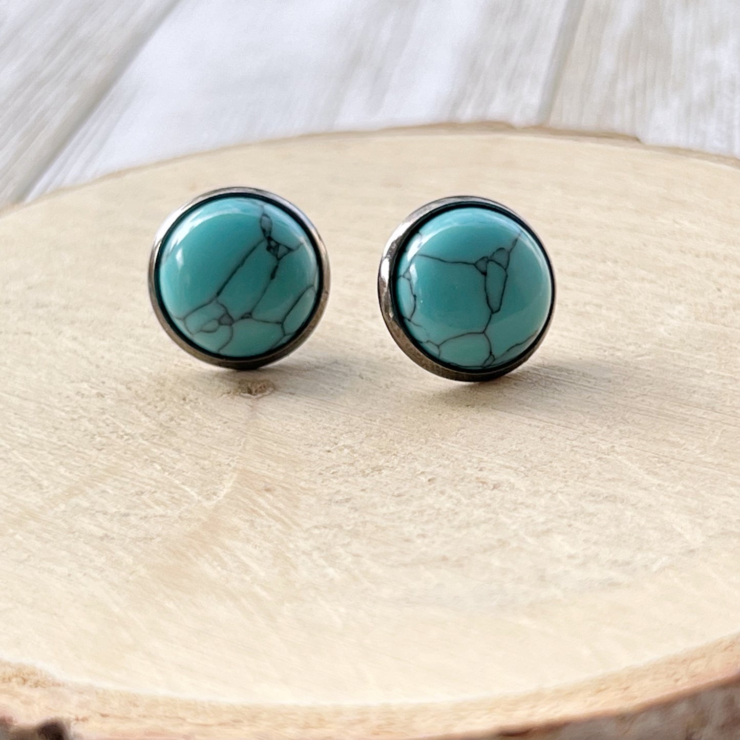 Turquoise 12mm Stud Earrings with Gunmetal Setting on wood display 