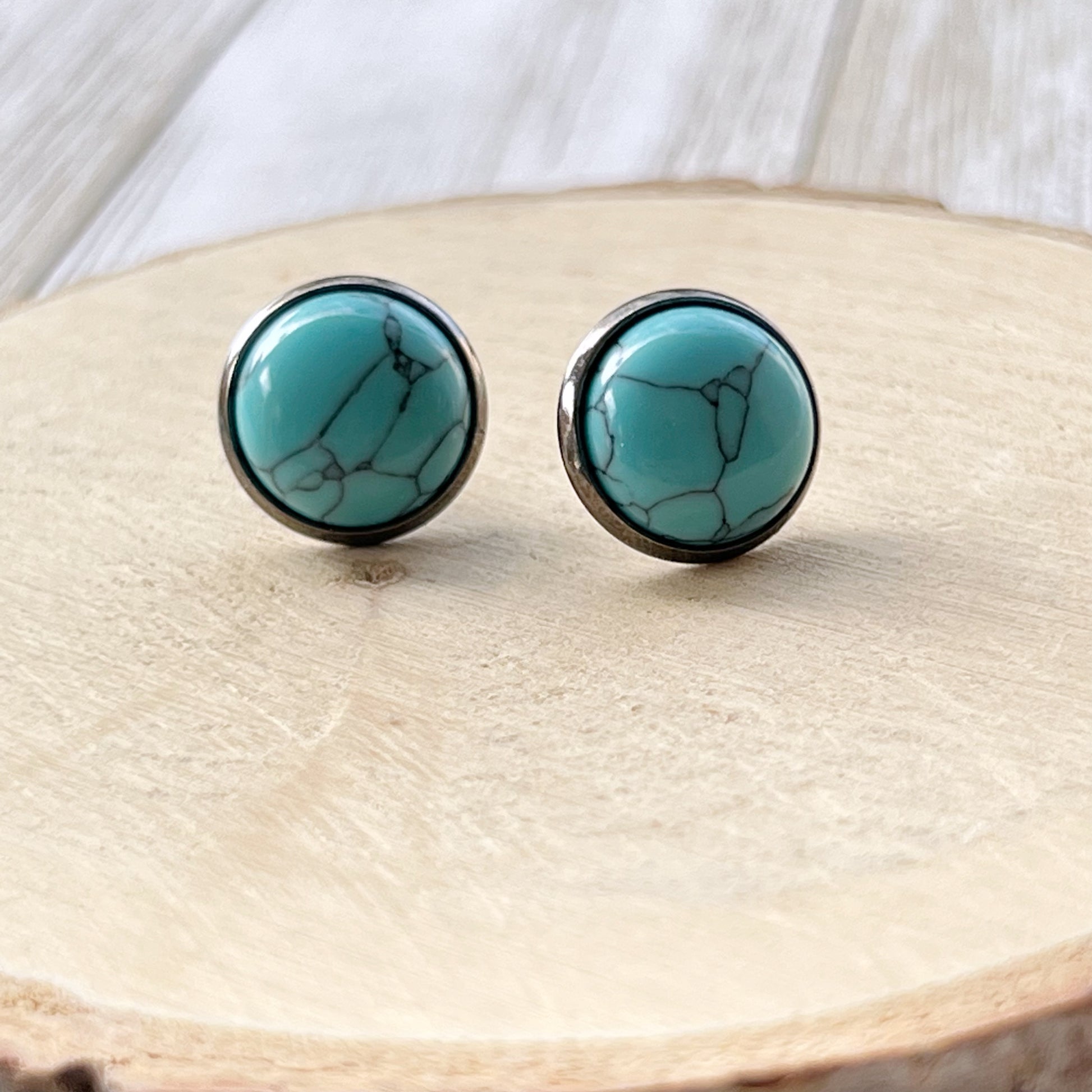 Turquoise 12mm Stud Earrings with Gunmetal Setting on wood display 