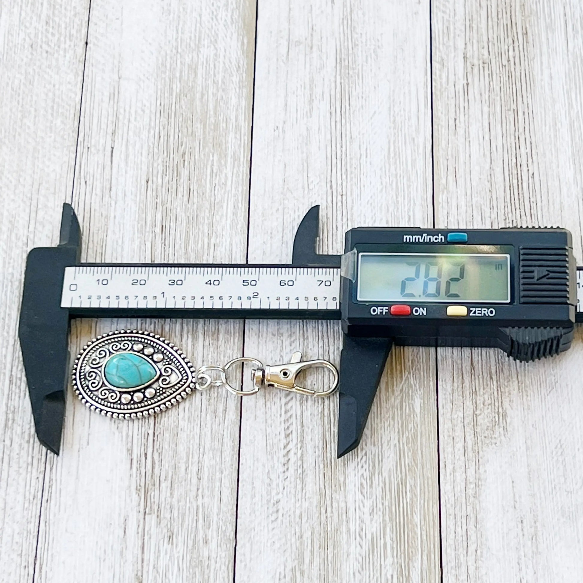 Silver western handbag charm with ornate medallion detail and faux turquoise accent length measurement