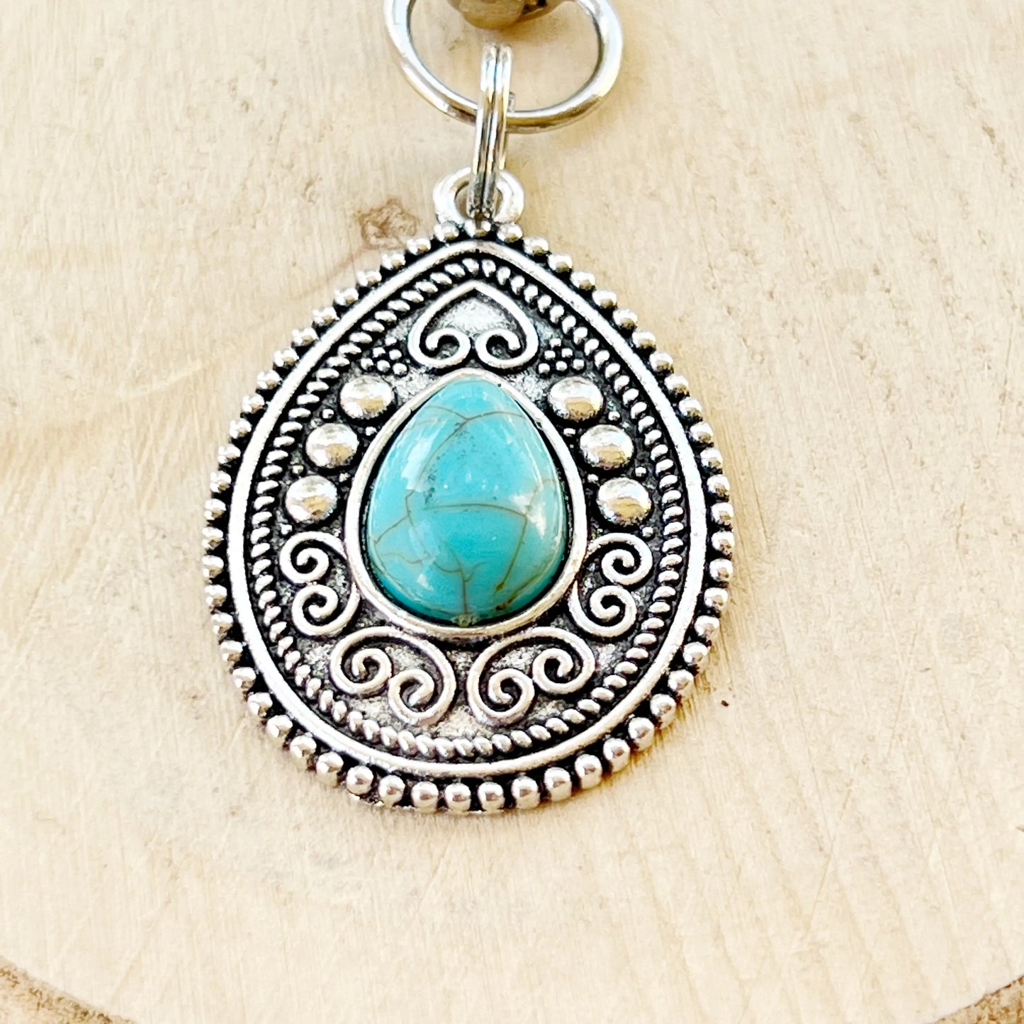 Silver western handbag charm with ornate medallion detail and faux turquoise accent close up details 