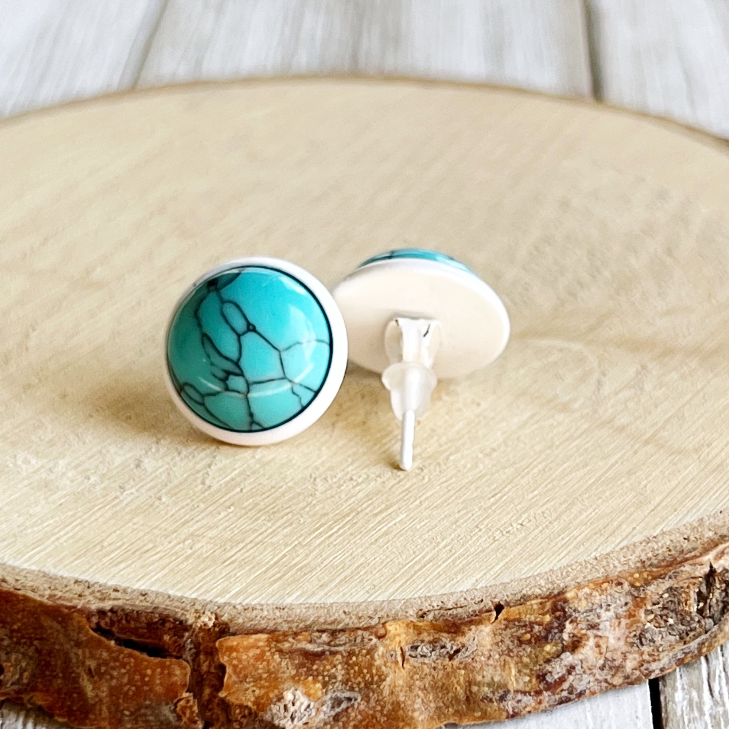 Round turquoise white stud earrings back of earrings displayed on a light wood background