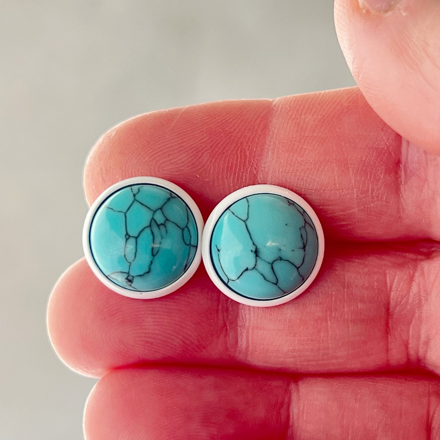 Round turquoise white stud earrings In hand for sizing scale