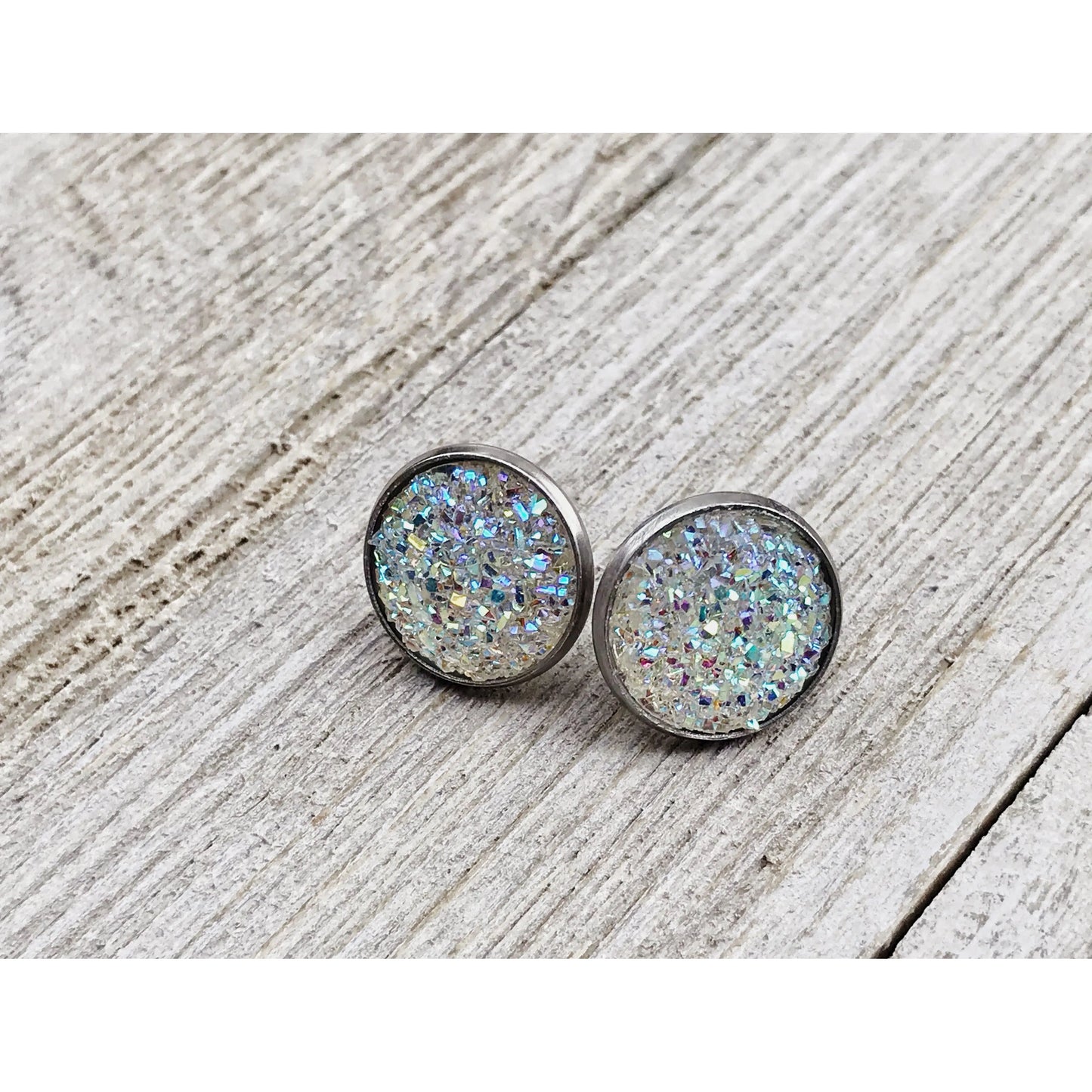 Round silver earrings with a glittery finish on a wooden surface