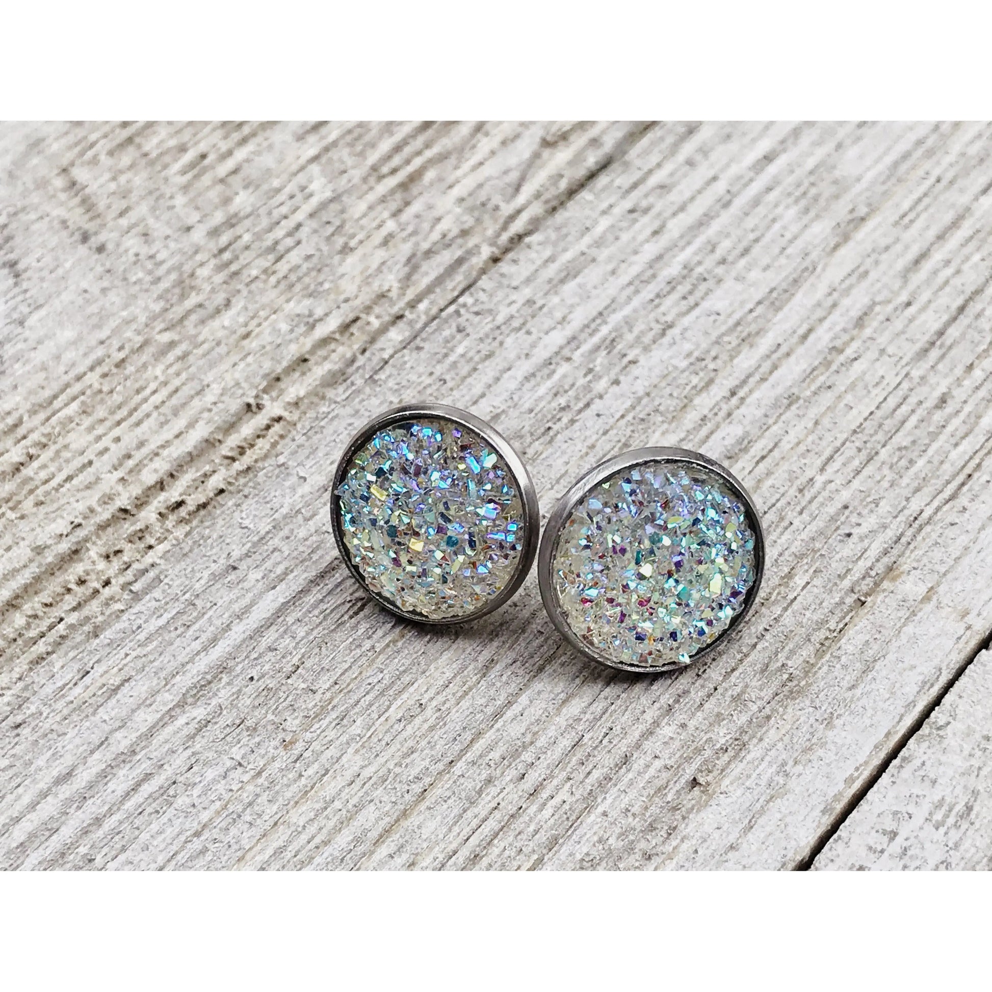 Round silver earrings with a glittery finish on a wooden surface